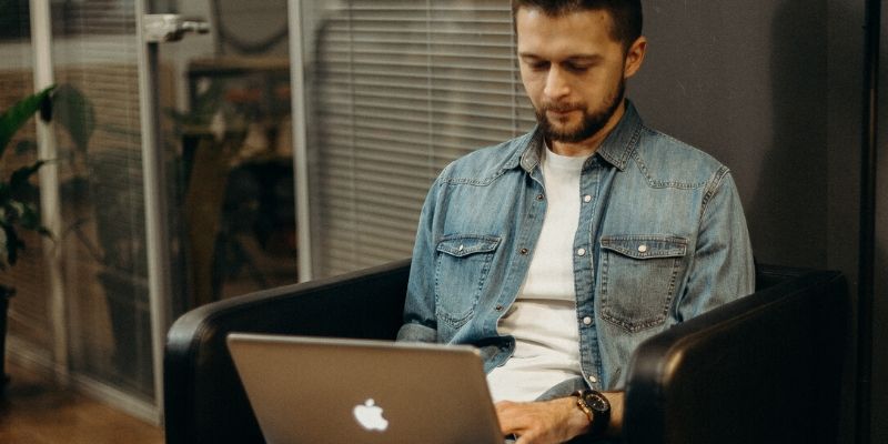 Man is sitting on his apple computer working SEO