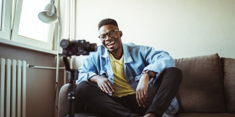 Young man is smiling in front a video camera getting ready to run a Youtube ad