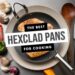 A HexClad pan with a perfectly cooked chicken breast is surrounded by a knife, wooden spoon, garlic, mushrooms, and bell peppers on a stainless steel surface. Text in the center proudly reads, The Best HexClad Pans for Cooking.” Experience the pinnacle of Hexclad cooking today.