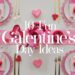 A festive table setup with white plates, pink hearts, and red accents sets the mood for Galentines Day. Pink and red decorations adorn the table alongside flowers. Text overlay reads, 10 Fabulous Galentines Day Ideas.