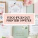 A flat lay of eco-friendly printed invites is artfully arranged. At the center, a pink box proudly displays 5 Eco-Friendly Printed Invites. Surrounding it, floral-themed invitations with green, pink, and white accents embrace nature’s beauty without waste, enhanced by decorative plant elements.