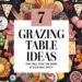 A colorful, show-stopping grazing table layout showcases assorted cheeses, fruits, and nuts, all surrounding a central text: 7 Grazing Table Ideas That Will Steal the Show at Your Next Party. Plates, cutlery, and glasses are symmetrically arranged to complement the display.