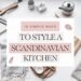 A flat lay of kitchen items like cutting boards, knives, plants, and linens frames a text box reading 10 Simple Ways to Style a Scandinavian Kitchen. The design captures the clean, minimalist aesthetic characteristic of Scandinavian style.