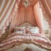 A luxurious vintage princess bedroom with a grand, ornate canopy bed draped in pink lace. The elegantly ruffled bedding and a crystal chandelier above add to the fairytale retreat. A vintage mirror and delicate furniture complete the sophisticated look of timeless elegance.