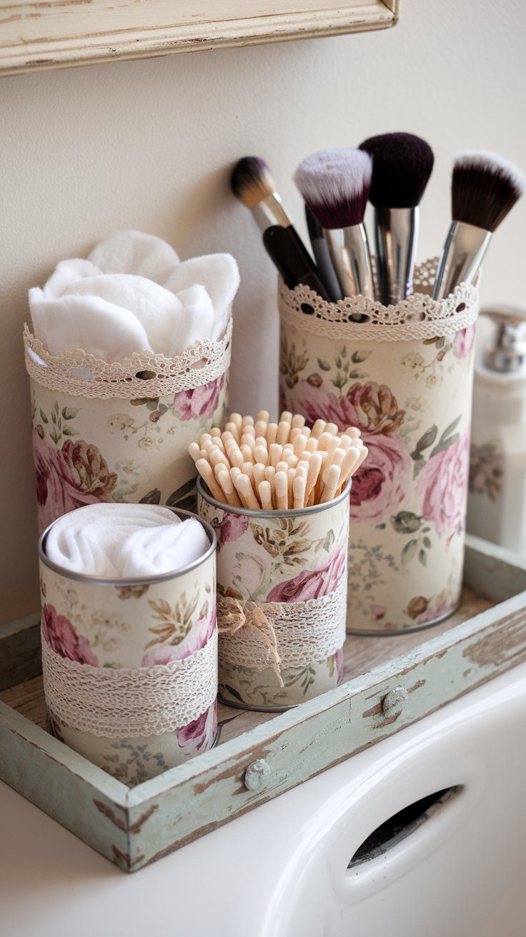 Transform your bathroom with vintage-inspired DIY organizers: decoupaged tin cans adorned with lace and rustic floral designs neatly hold cotton pads, swabs, and makeup brushes, blending charm with clever storage solutions.