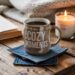 A mug labeled COZY MOMENTS rests on handmade denim coasters beside a glowing candle and an open book, all set atop a wooden table with a knitted blanket in the background—inviting you into a scene of warmth, comfort, and relaxation.