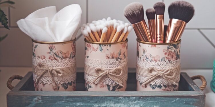 Transform ordinary tin cans into charming bathroom organizers with this DIY project: floral lace decoupage adds elegance while neatly storing cotton pads, swabs, and makeup brushes—all presented on a stylish blue tray.