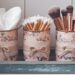 Transform ordinary tin cans into charming bathroom organizers with this DIY project: floral lace decoupage adds elegance while neatly storing cotton pads, swabs, and makeup brushes—all presented on a stylish blue tray.