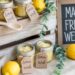A charming farmers market-inspired display showcases handmade lemon sugar scrubs in mason jars, accented with fresh lemons, greenery, and a welcoming “Made Fresh Weekly” chalkboard sign—capturing the essence of rustic freshness and artisanal care.