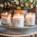 Three handmade citronella candles, labeled Outdoor summer candle, are displayed on a rustic metal tray—an inviting setup ideal for farmers markets. Set against a backdrop of greenery and natural light, they promise both charm and functionality for al fresco evenings.
