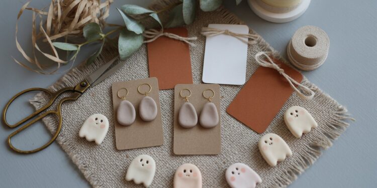 Discover inspiration for handmade crafts with this charming display of ghost-shaped clay earrings and charms, gift tags, ribbons, and dried foliage—an inviting flat lay that celebrates creative DIY projects.