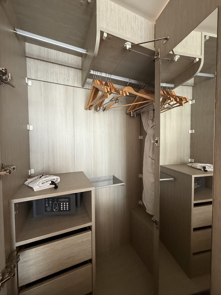 Perfect for cruise adventures, this wardrobe offers shelves, drawers, a safe, hangers, mirror, towel, and ironing board.