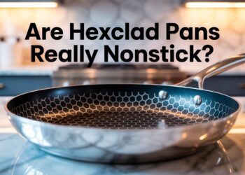 A HexClad pan with its signature hex pattern sits on marble in a sleek kitchen. Text asks if it’s truly nonstick or eggs will stick.