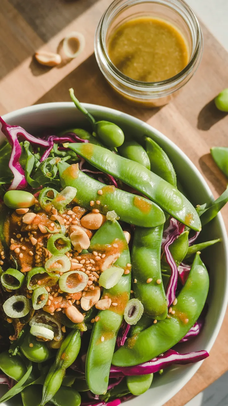 Snap peas, red cabbage, edamame, and peanuts top Salad 7, finished with sesame seeds and brown dressing on wood.