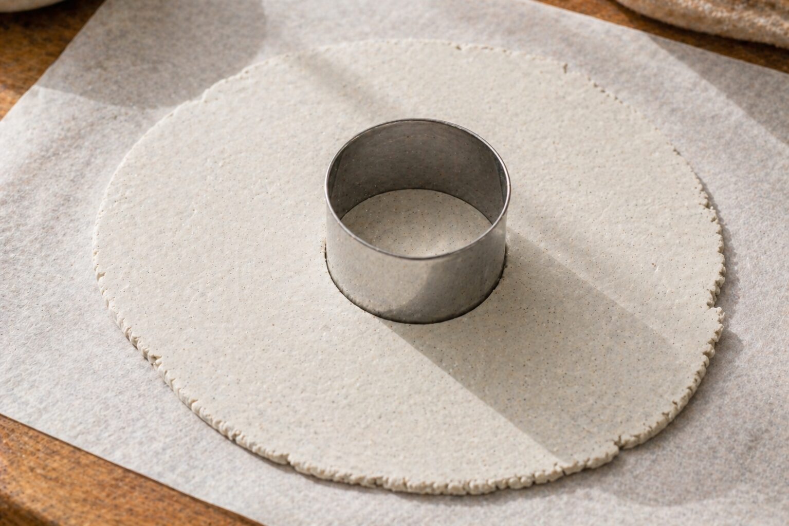 Round cookie cutter pressed into flat clay slab from above, showing a clean 4-inch circle cut ready to lift